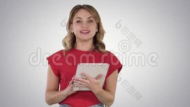 主持人女士穿着红色t恤，拿着平板电脑翻页，在渐变背景下与相机交谈。